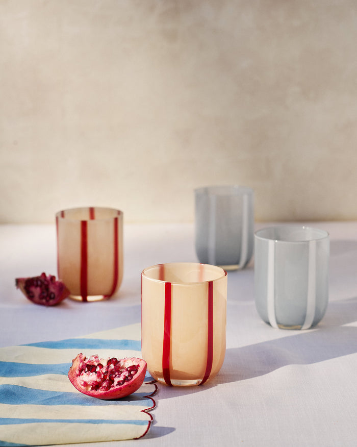 Demi striped drinking glasses with pomegranate on a linen table.