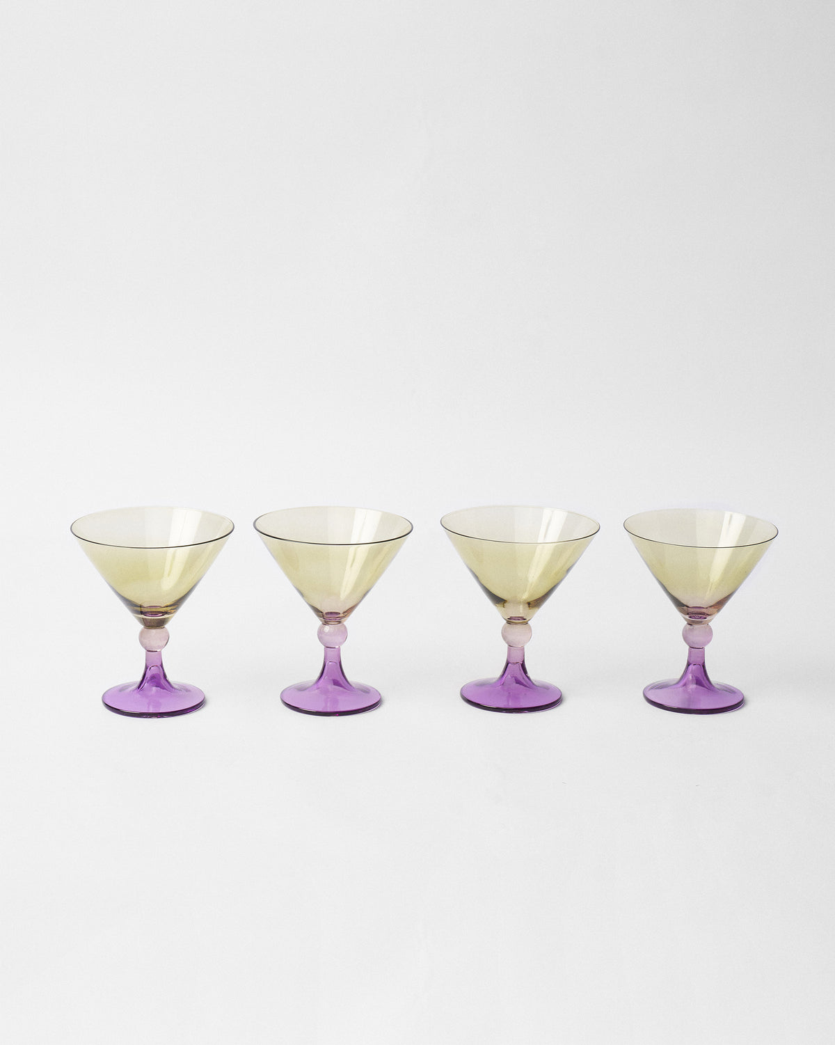 Set of four Mist cocktail glasses lined up with purple stems.