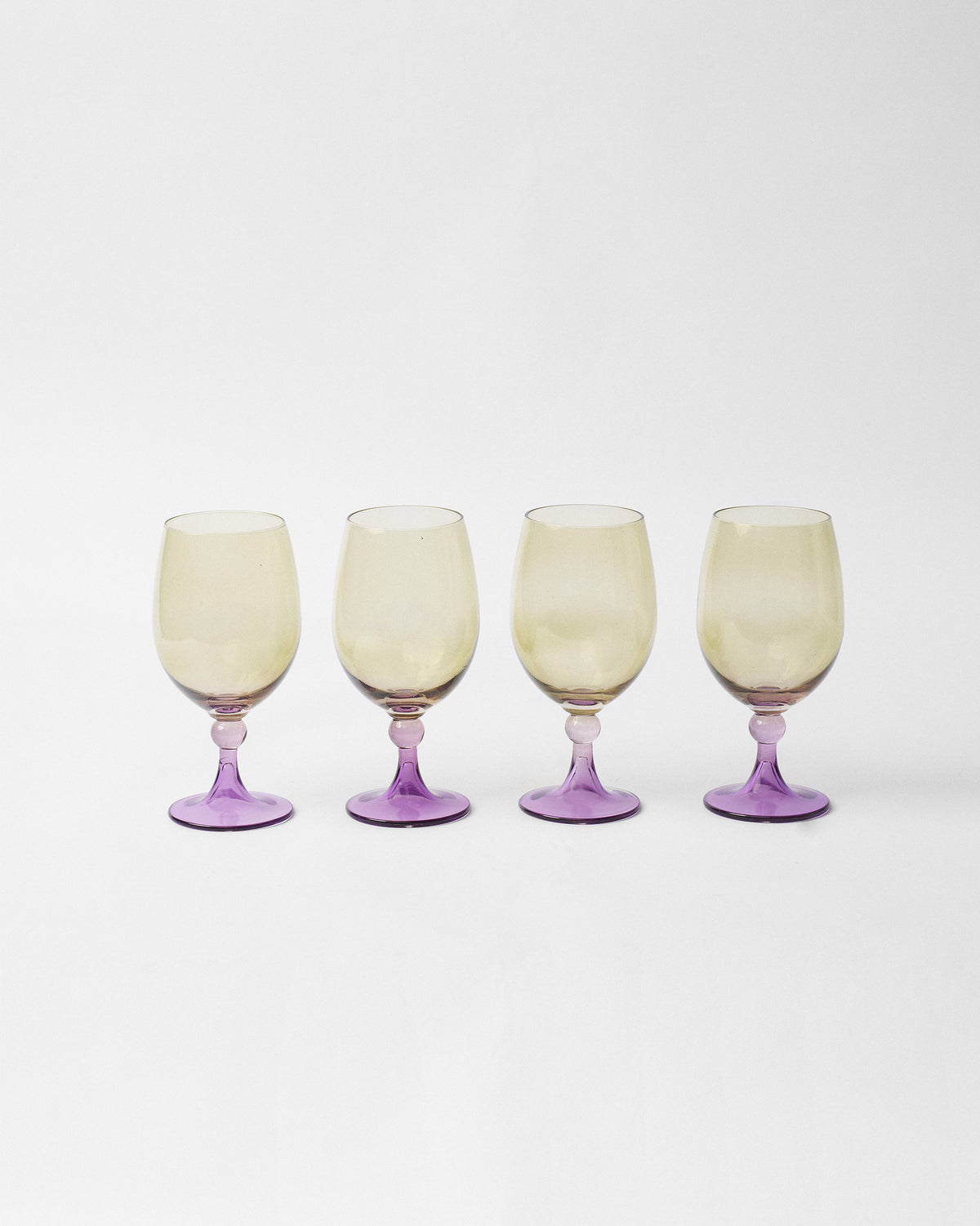 Four Cairo gin goblets lined up with amber bowls and purple stems.
