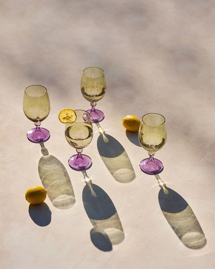 Set of four Cairo gin goblets with amber bowls and purple stems beside lemons.