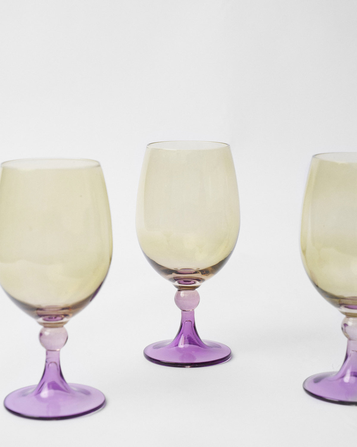 Close-up of Cairo gin goblets with purple knop stems and amber bowls.
