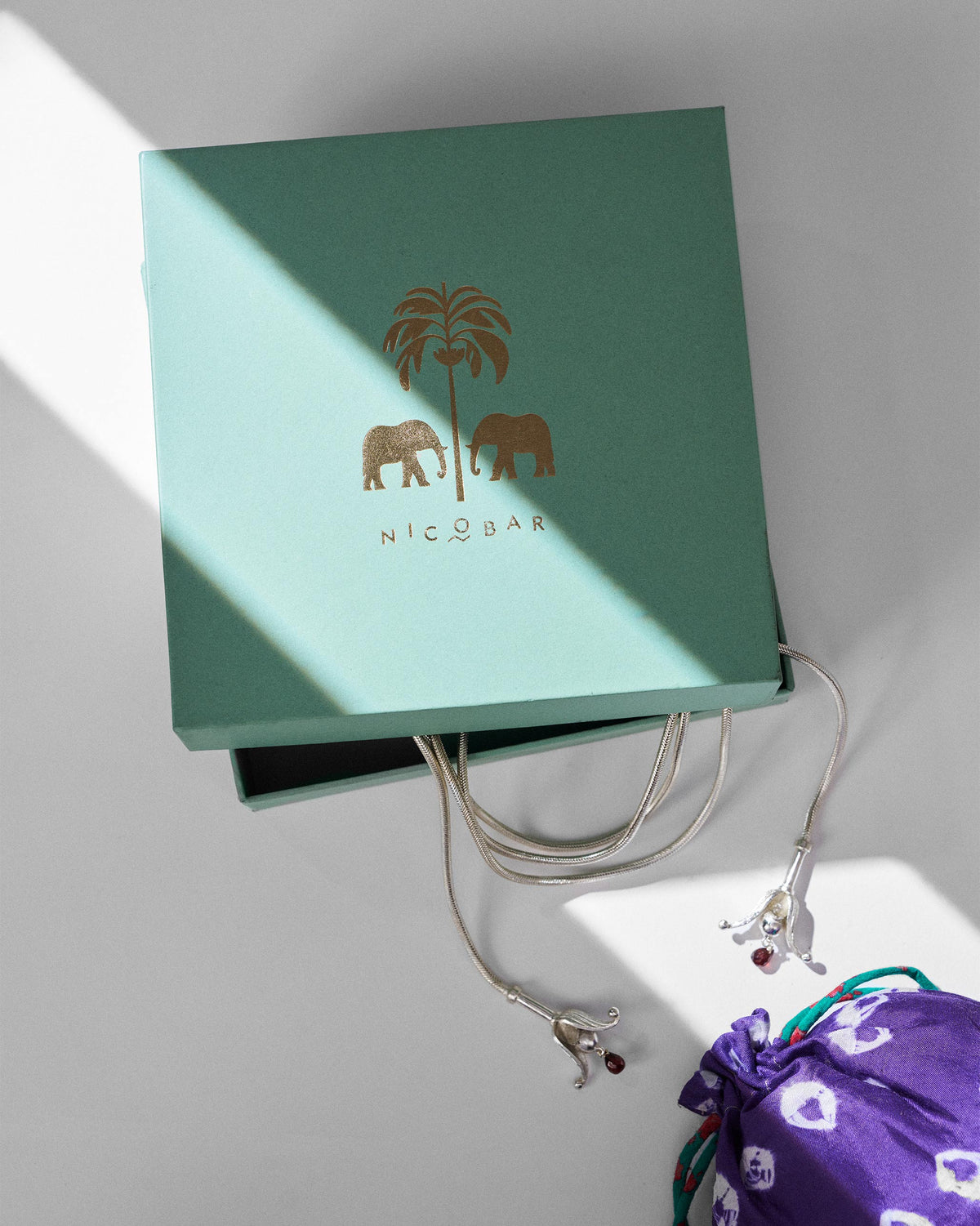 Silver Phool chain beside a green Nicobar gift box.