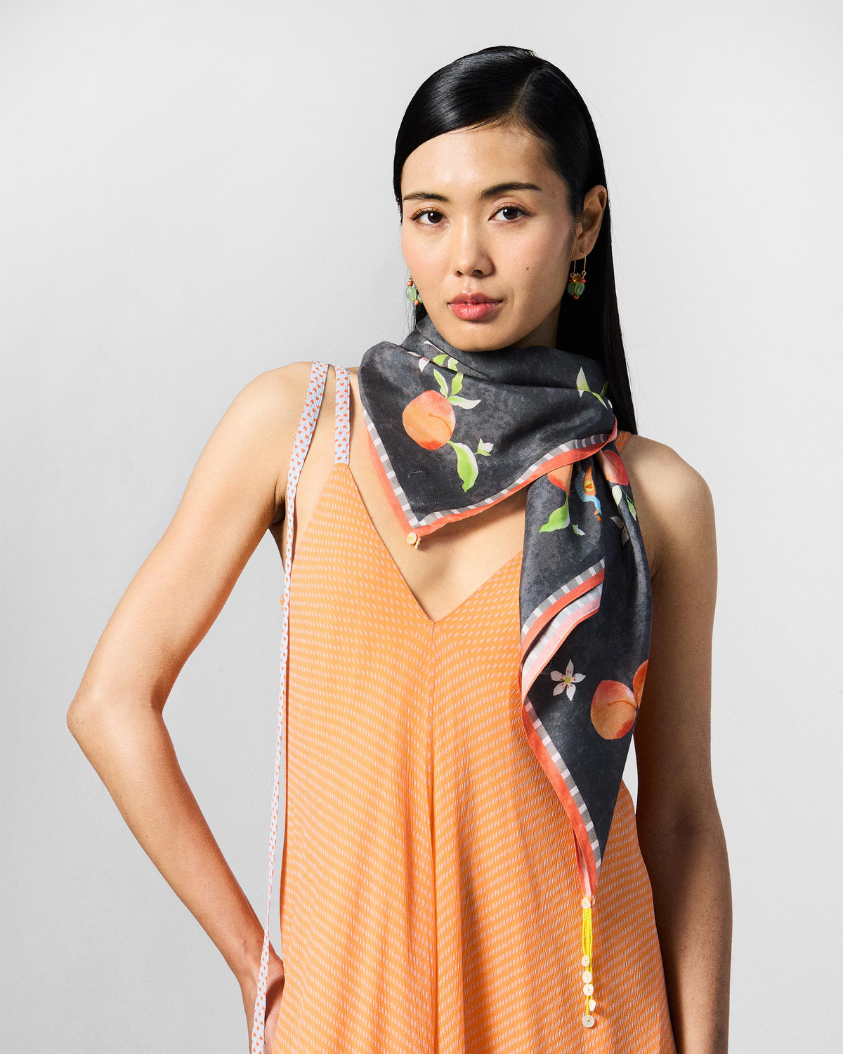 Person wearing a charcoal Apricot Scarf with peach print at the neck.