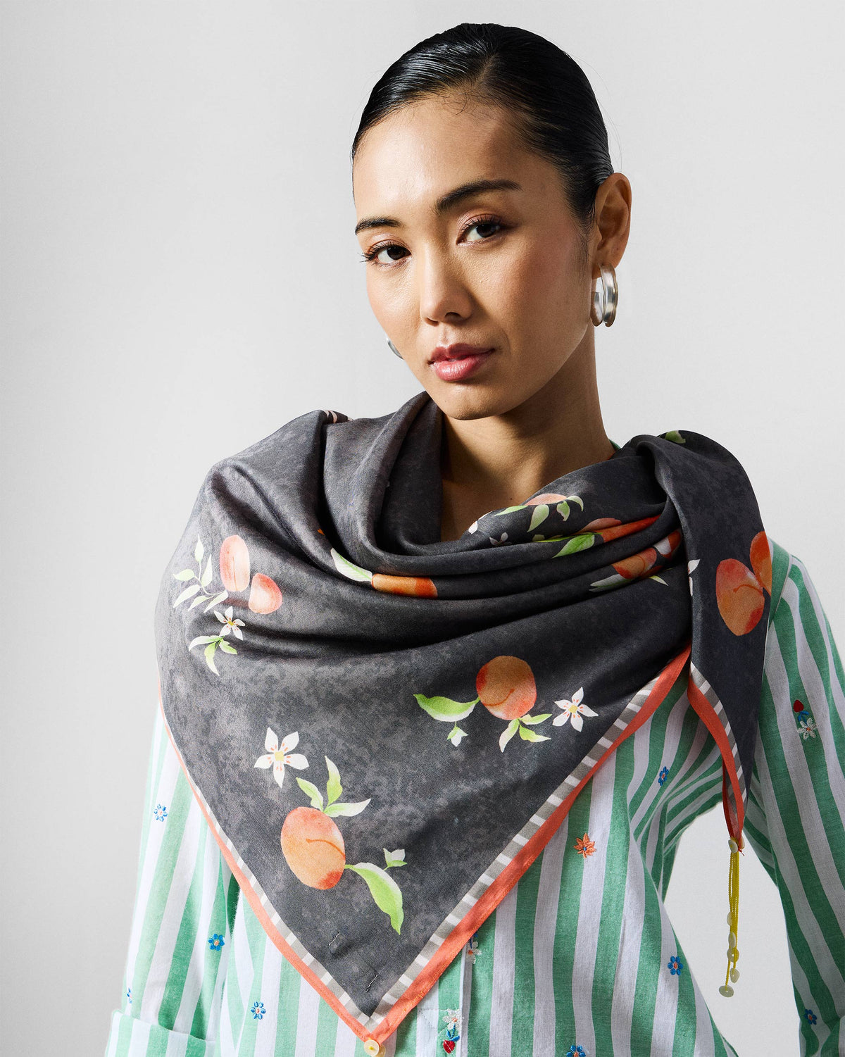 Person wearing a charcoal Apricot Scarf with peach print over the shoulders.