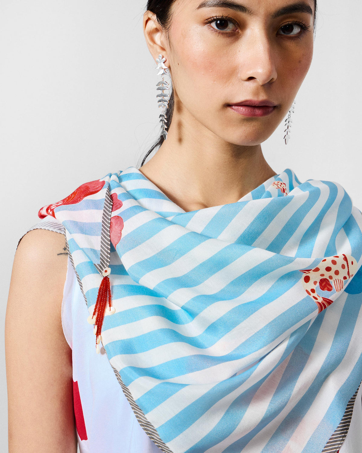Close-up of the Fields Scarf draped at the neck with a red beaded tassel.