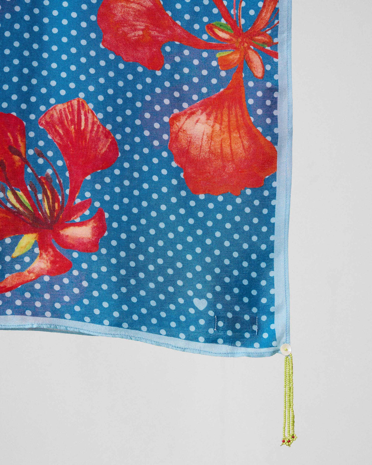 Close-up of the Gulmohar Scarf's red blossoms and beaded tassel on blue dots.