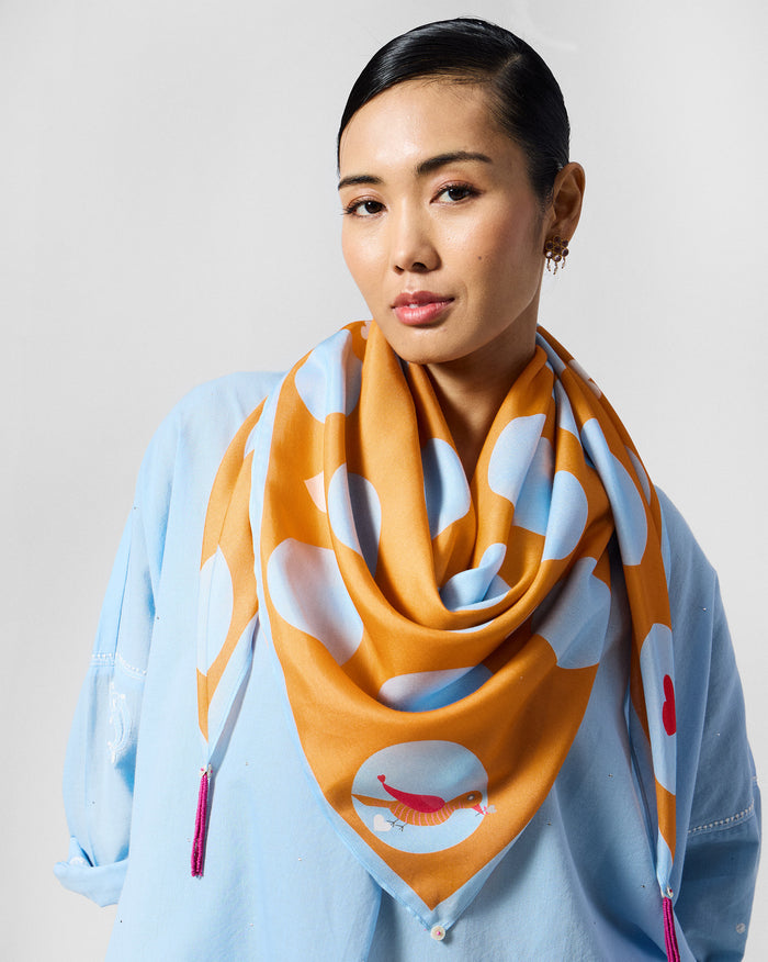 Person wearing an orange Dotty scarf with ice blue dots.