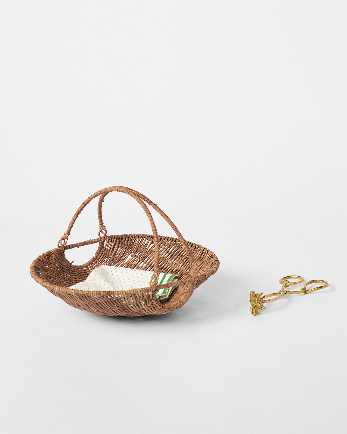Boat-shaped rattan bread basket with napkin and gold serving tongs.