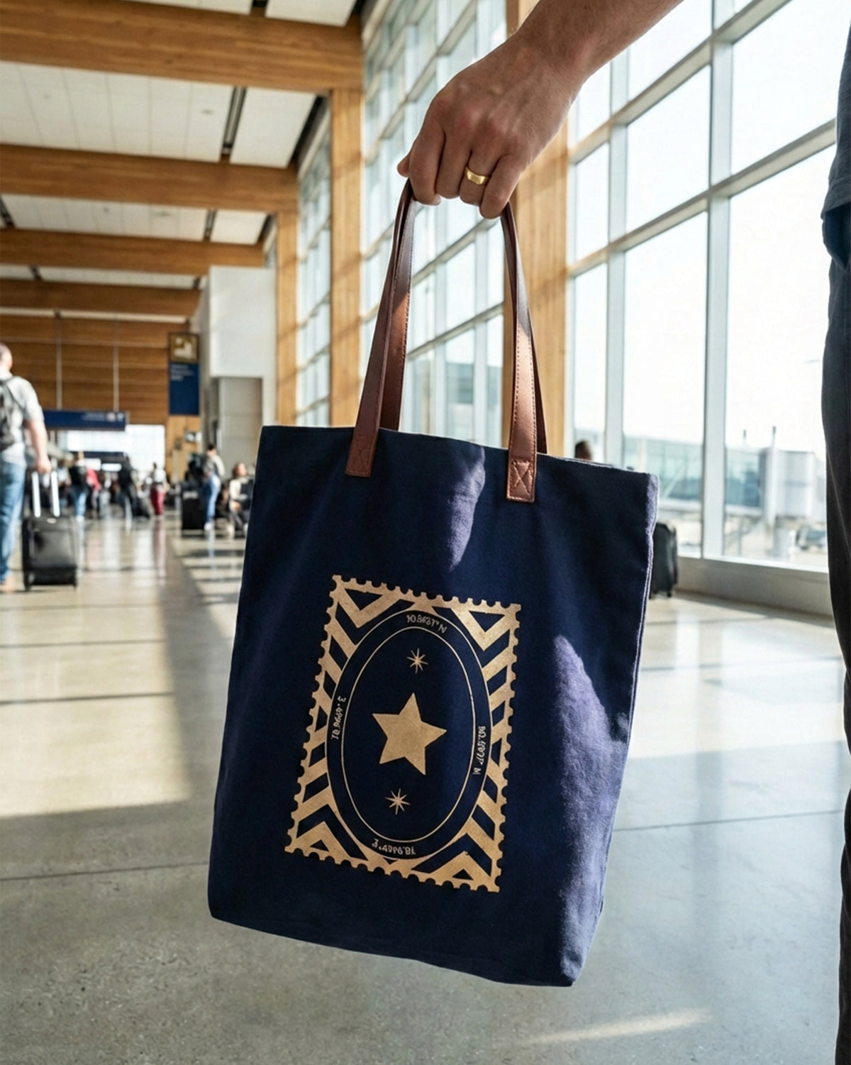 Navy Mukayu City tote with a gold star stamp held by its straps.
