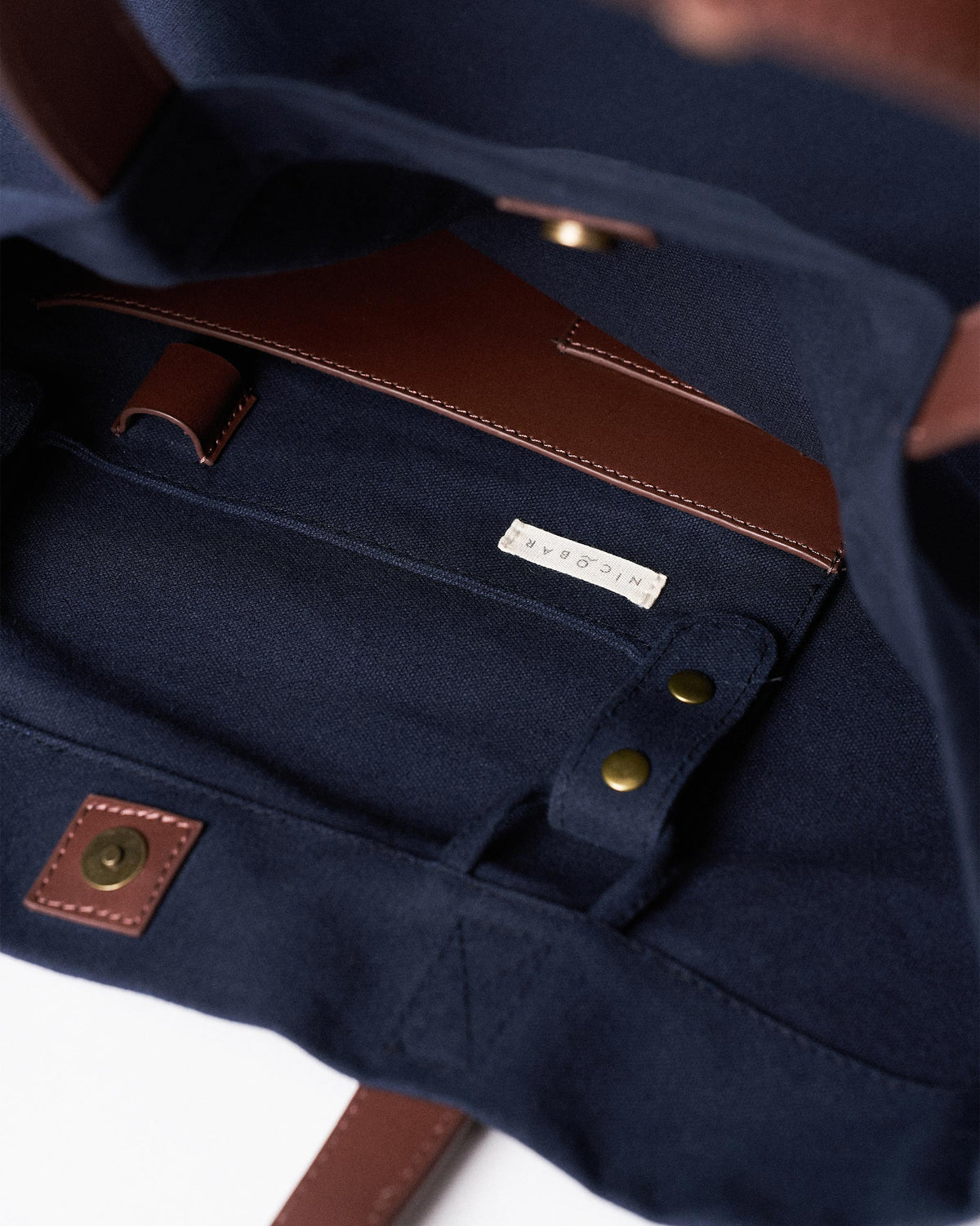 Interior of a navy Mukayu City tote with a leather-trimmed pocket.