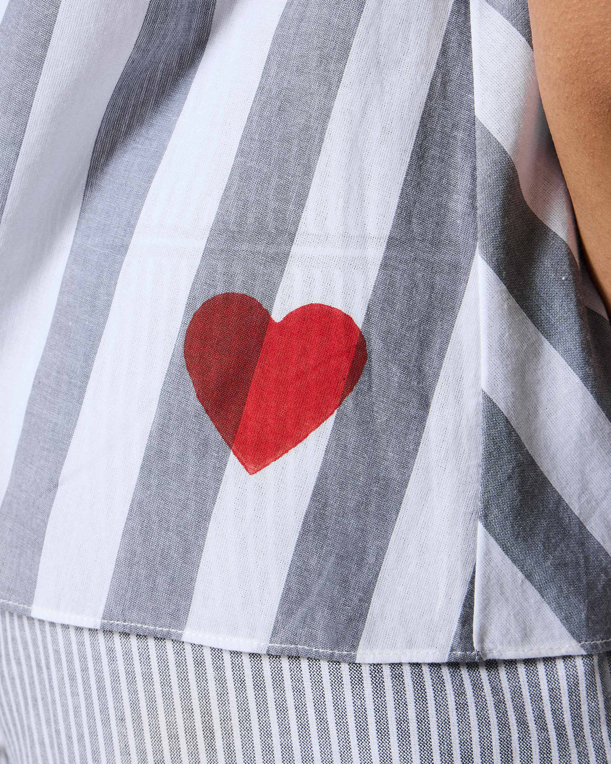 Close-up of a red heart on a grey and white striped Rann shirt.
