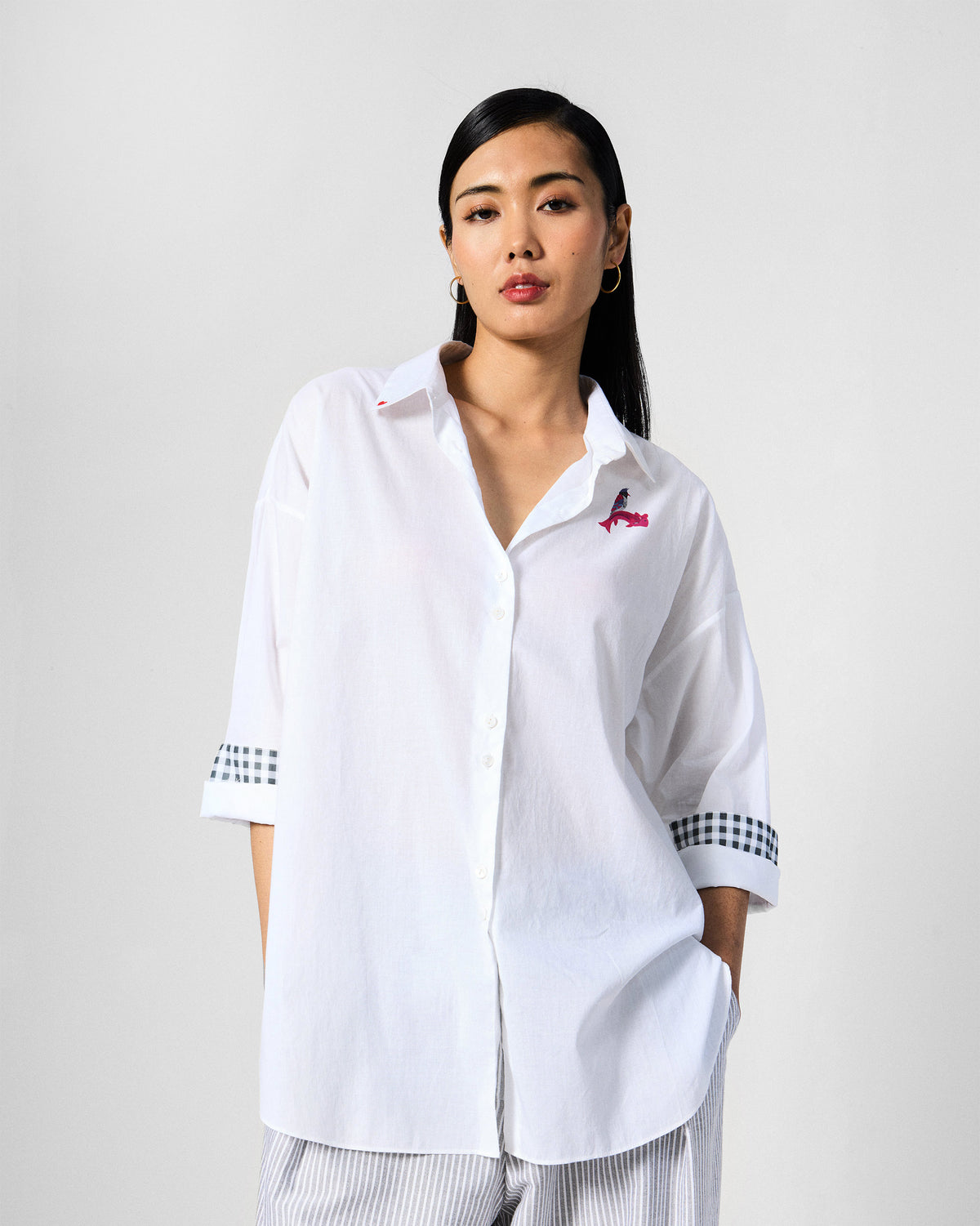 Person wearing a white Siv shirt with a pink bird on the chest.