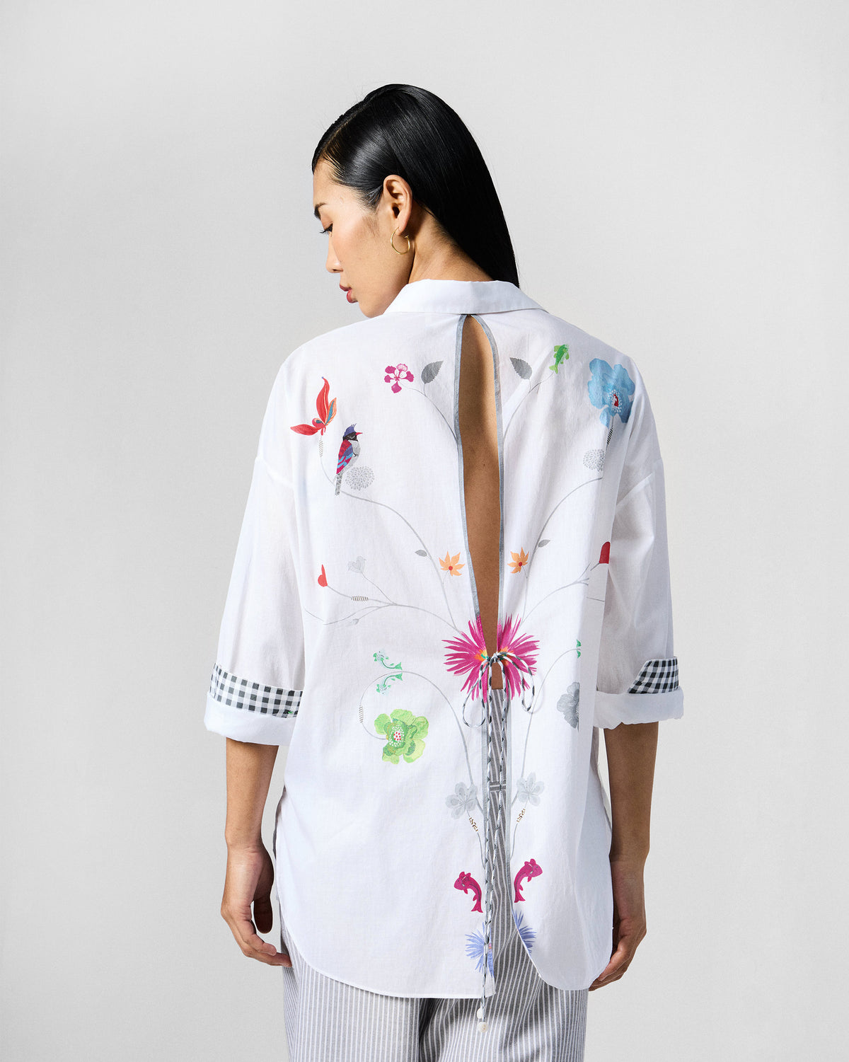 Back of a white Siv shirt with a cutout and colourful bird print.