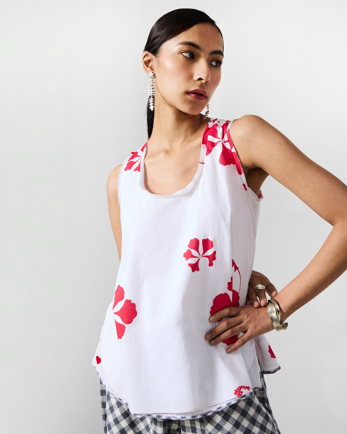 Person wearing a white Kiva top with large red hibiscus flowers.