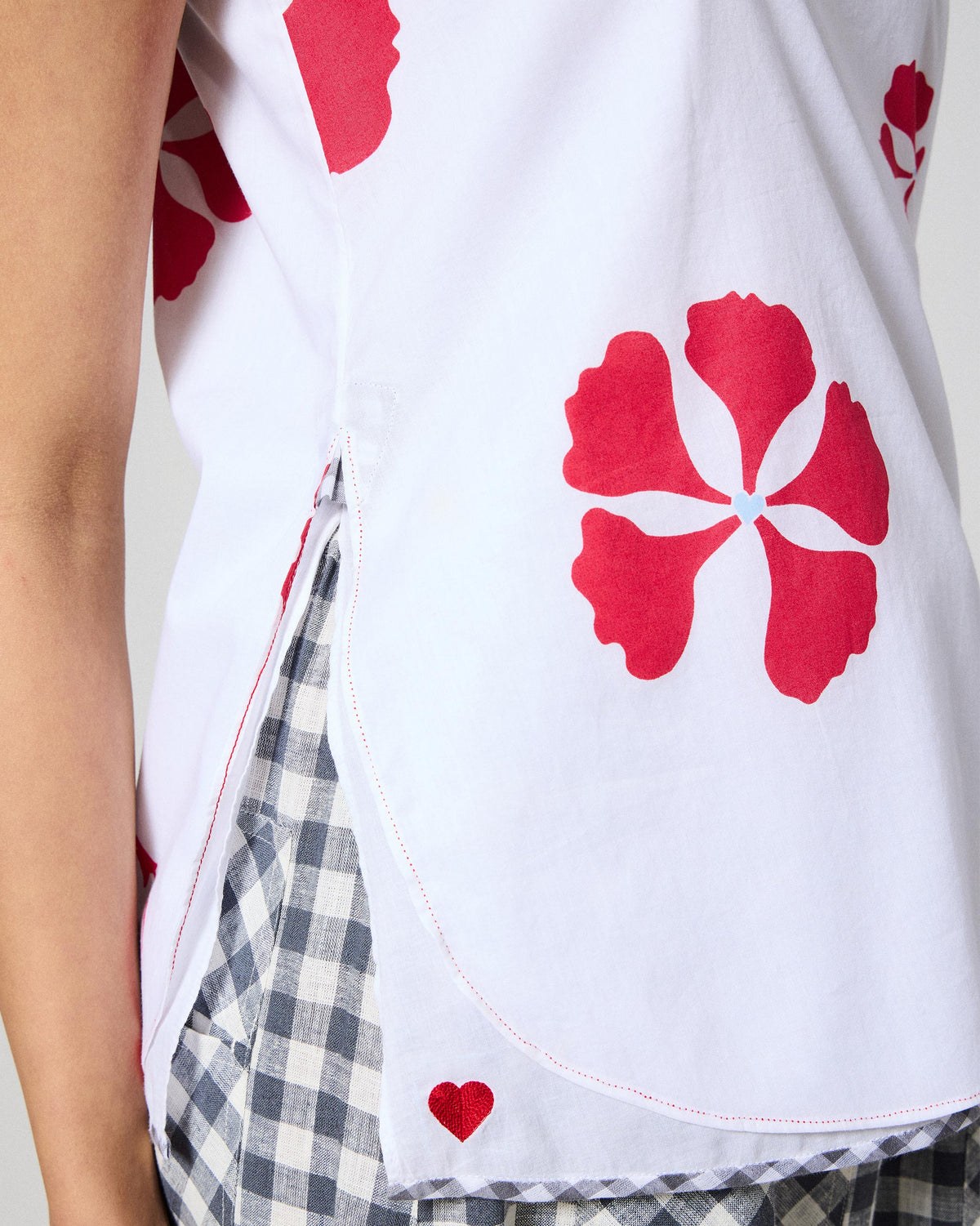 Close-up of the Kiva top hem with a red embroidered heart and side slit.