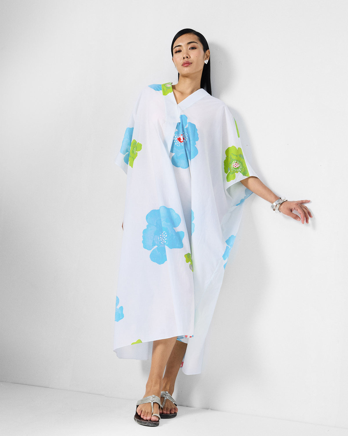 Person wearing a white Bea kaftan with blue and lime floral print.