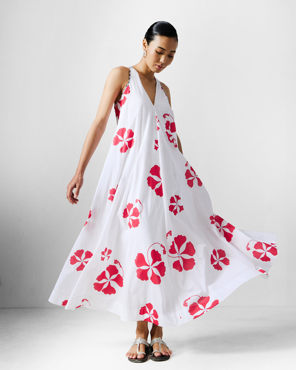Person wearing a white Anya Dress with a red gulmohar print.