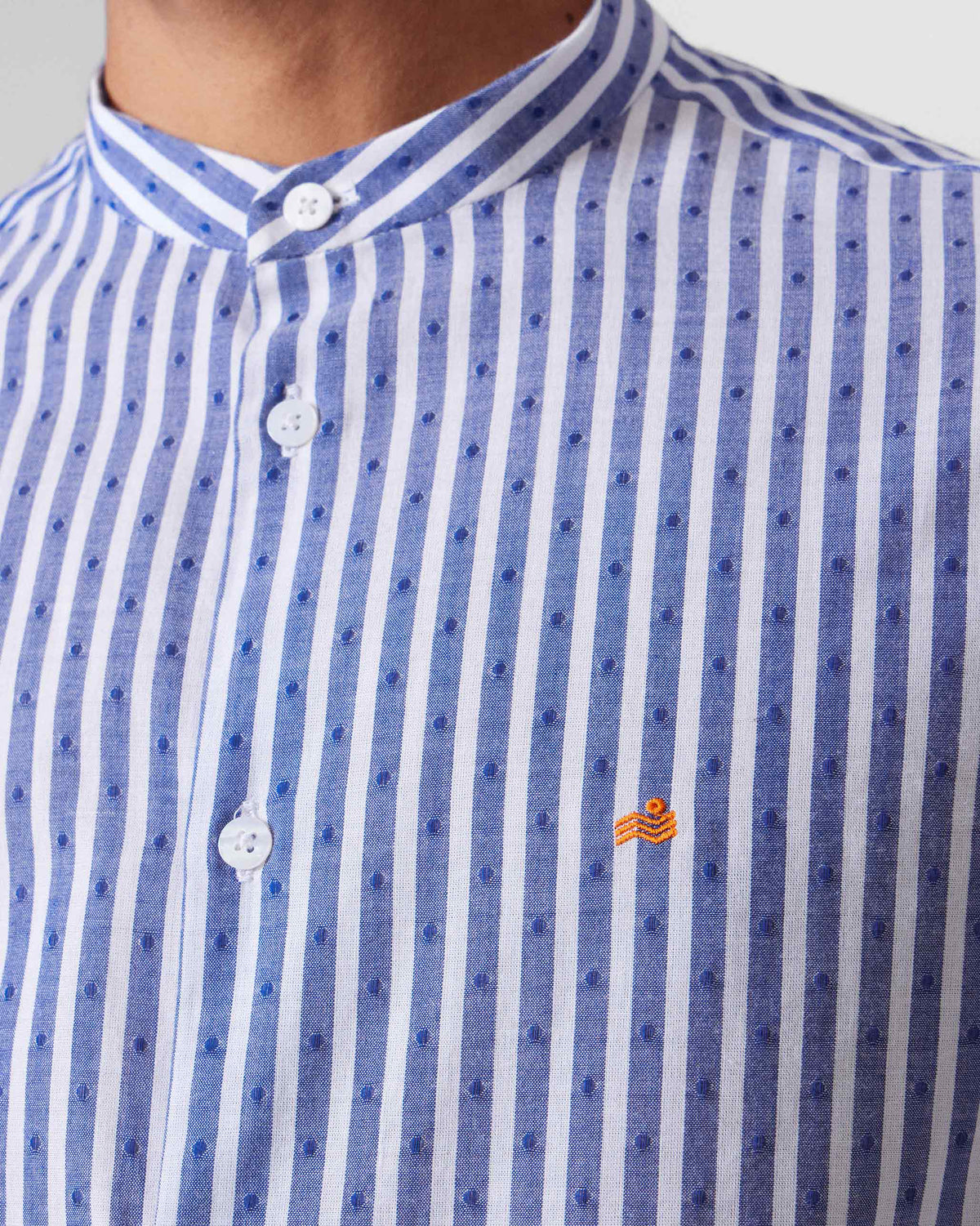 Close-up of a striped Nawab shirt showing the Nehru collar and orange logomark.