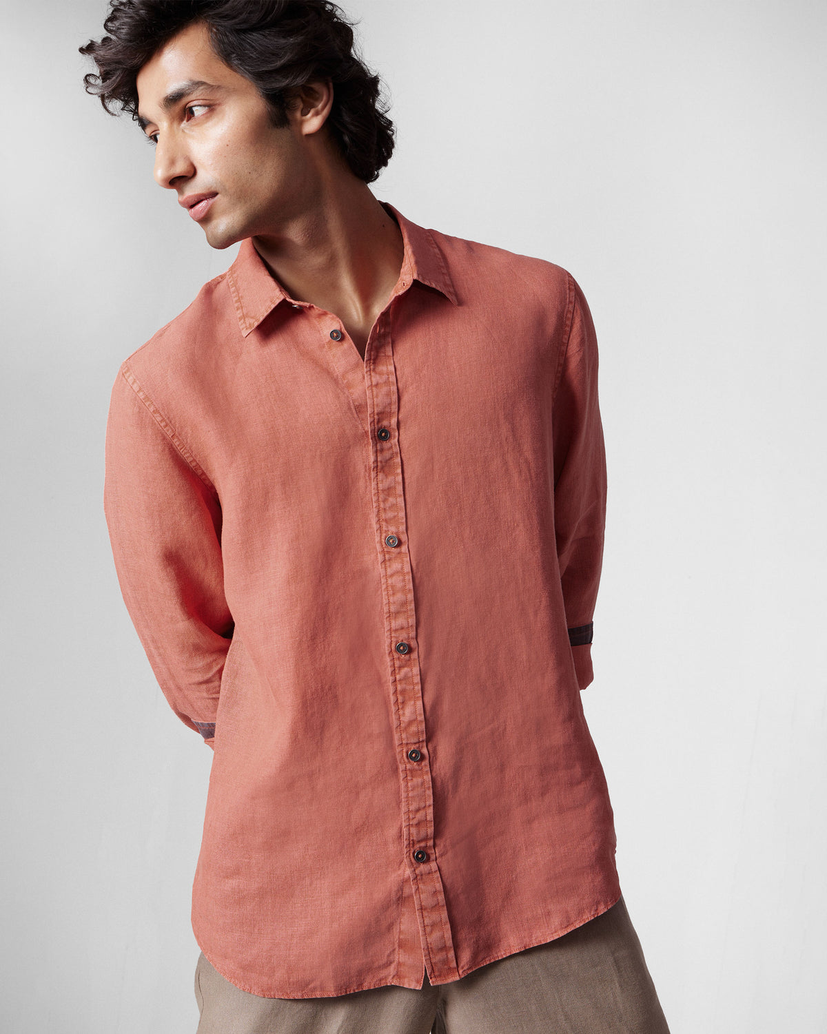 Person wearing a rust Indus Shirt with rolled sleeves showing a dark contrast cuff.