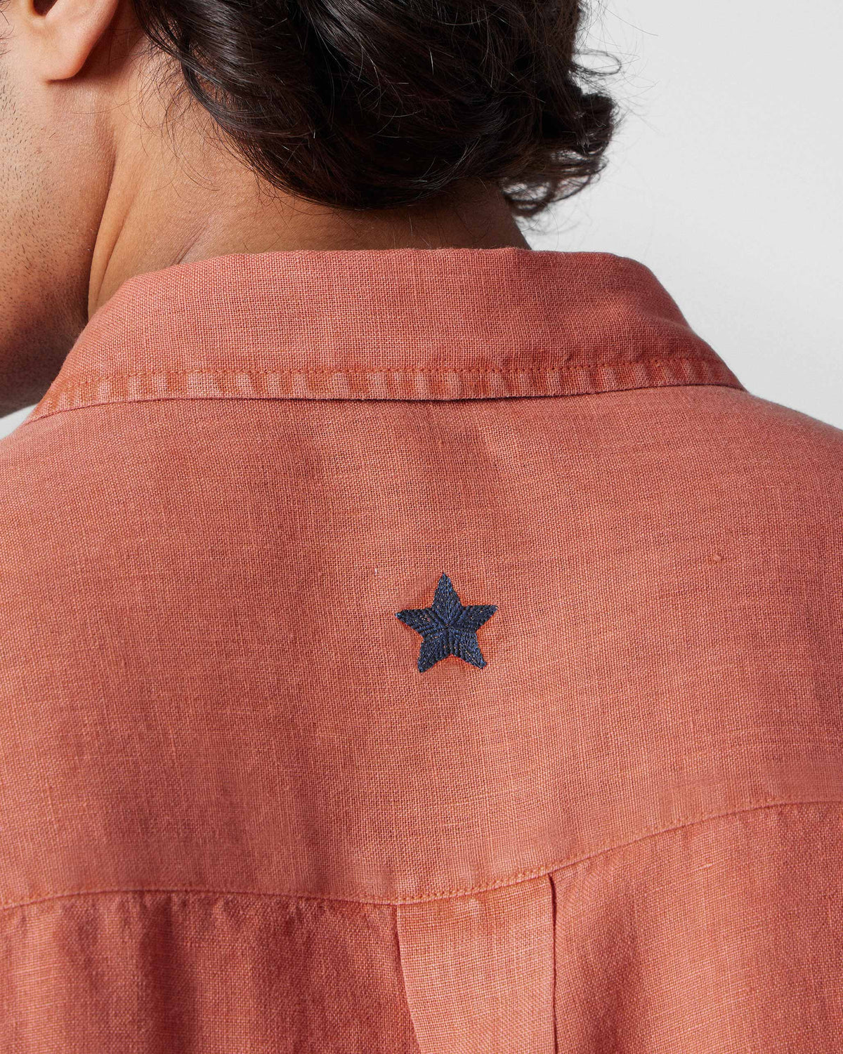 Close-up of the navy embroidered star on the back of a rust Indus Shirt.