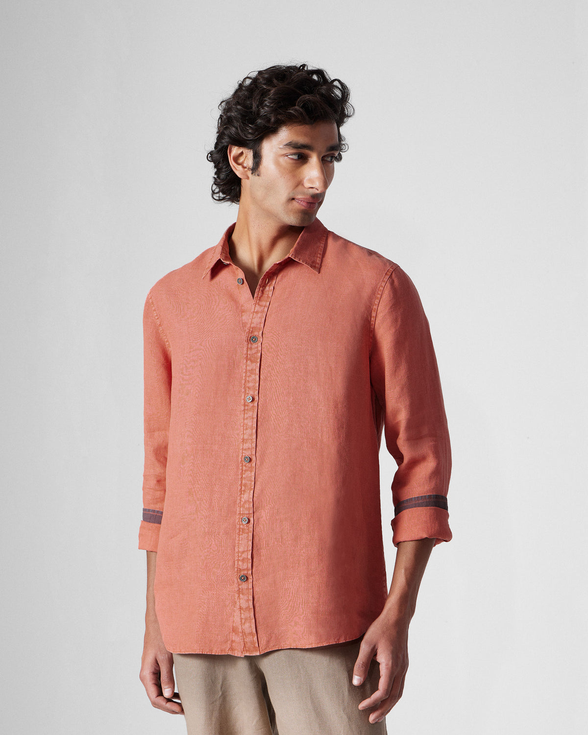 Person wearing a rust Indus Shirt with dark buttons and a contrast cuff band.