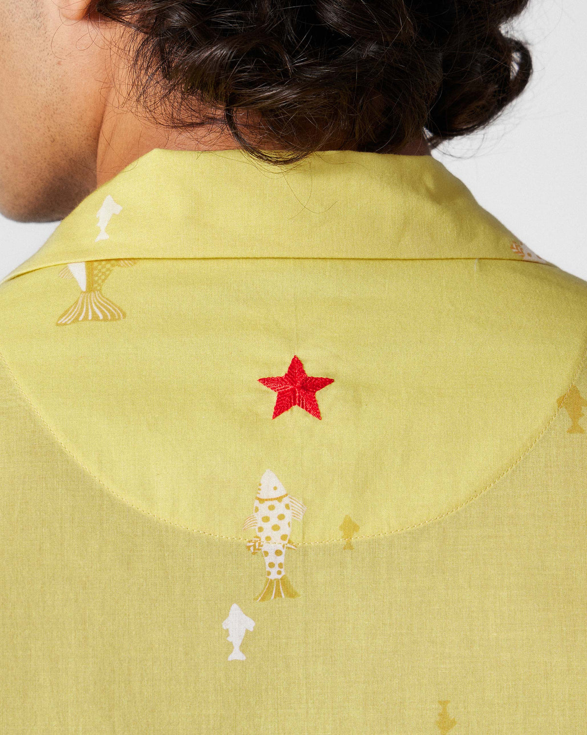 Close-up of the red embroidered star on the back of a light yellow Mistari Shirt.