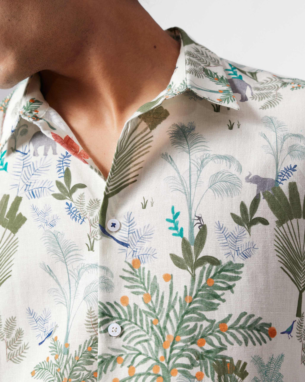 Close-up of a multicolour half-sleeve shirt showing monkeys, elephants, and palms.