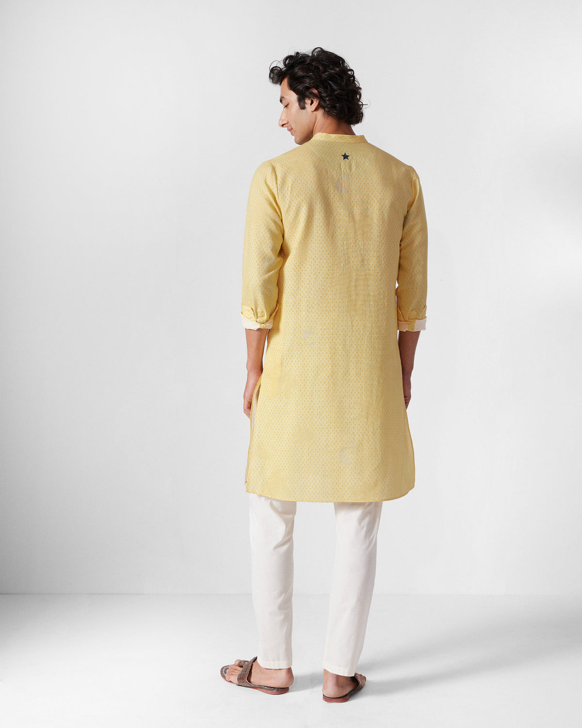 Back of a light yellow Astral kurta with a dark star on the yoke.