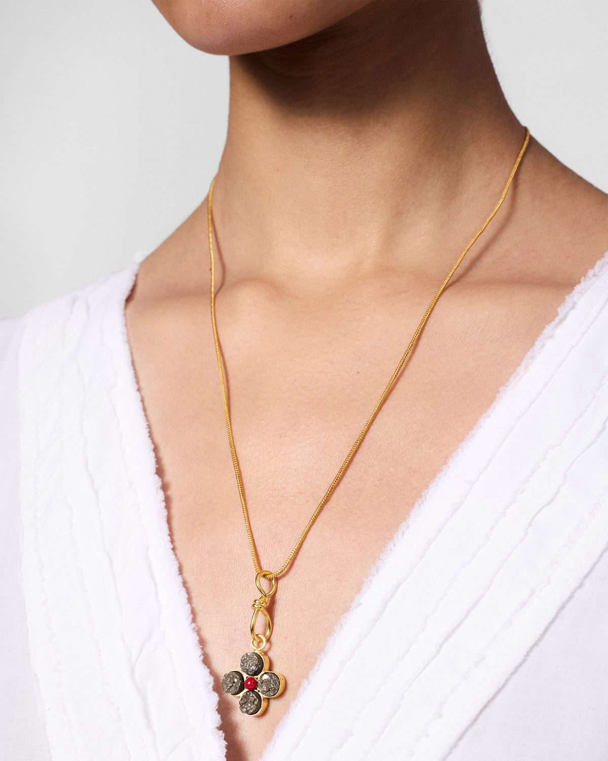 Gold Sindhu necklace with a four-petal flower pendant and red centre worn at the chest.