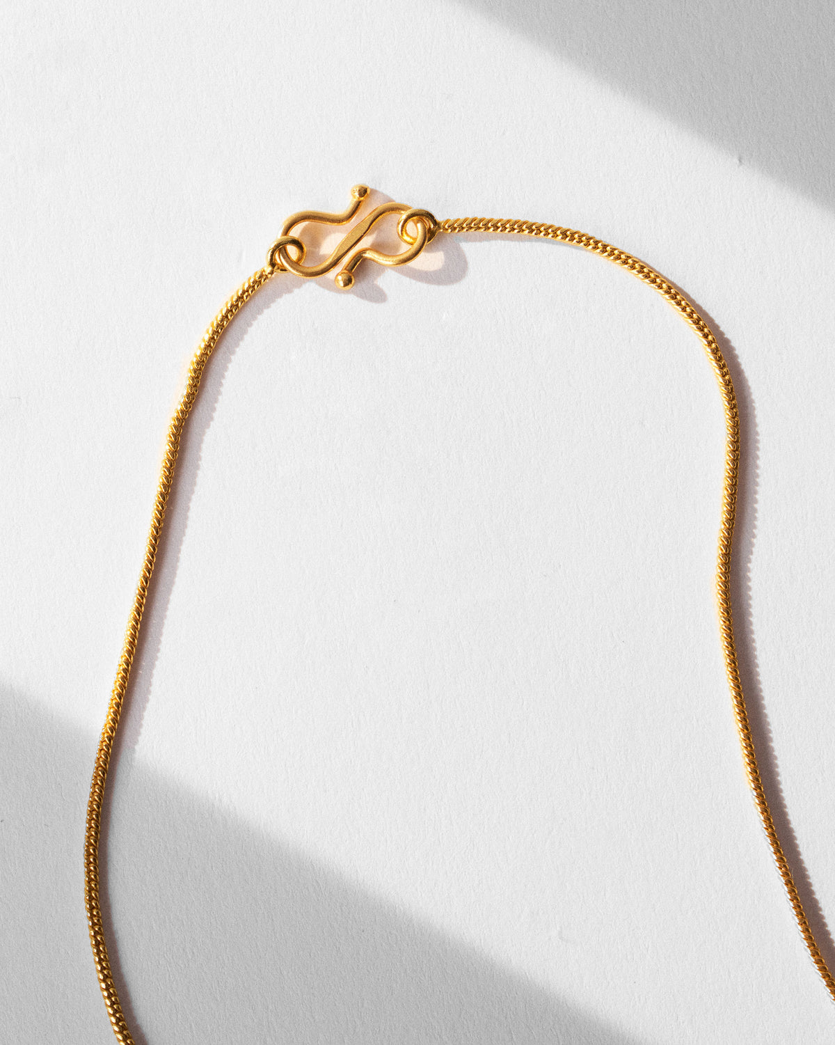 Close-up of the gold Sindhu necklace snake chain and S-hook clasp.