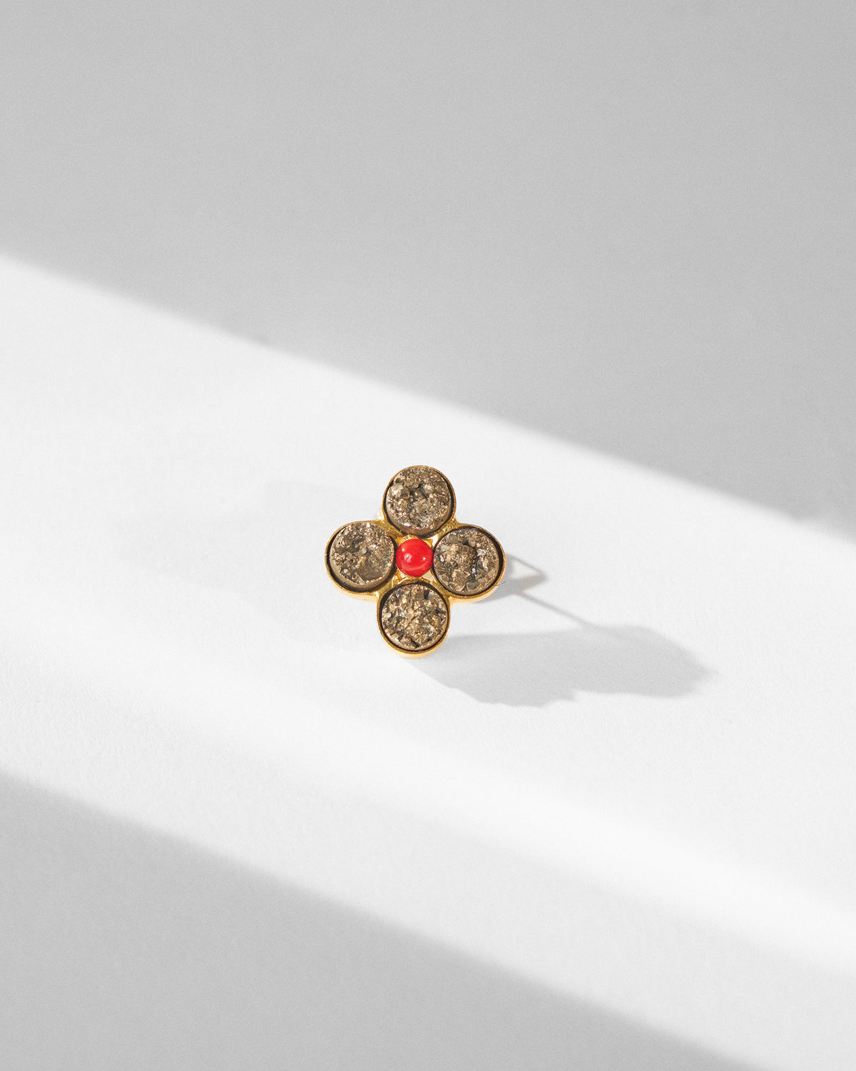 Sindhu gold flower ring with textured grey stones and a red centre bead.