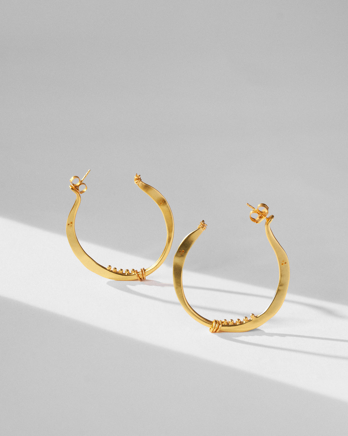 Pair of large gold Qala balis with bead accents.