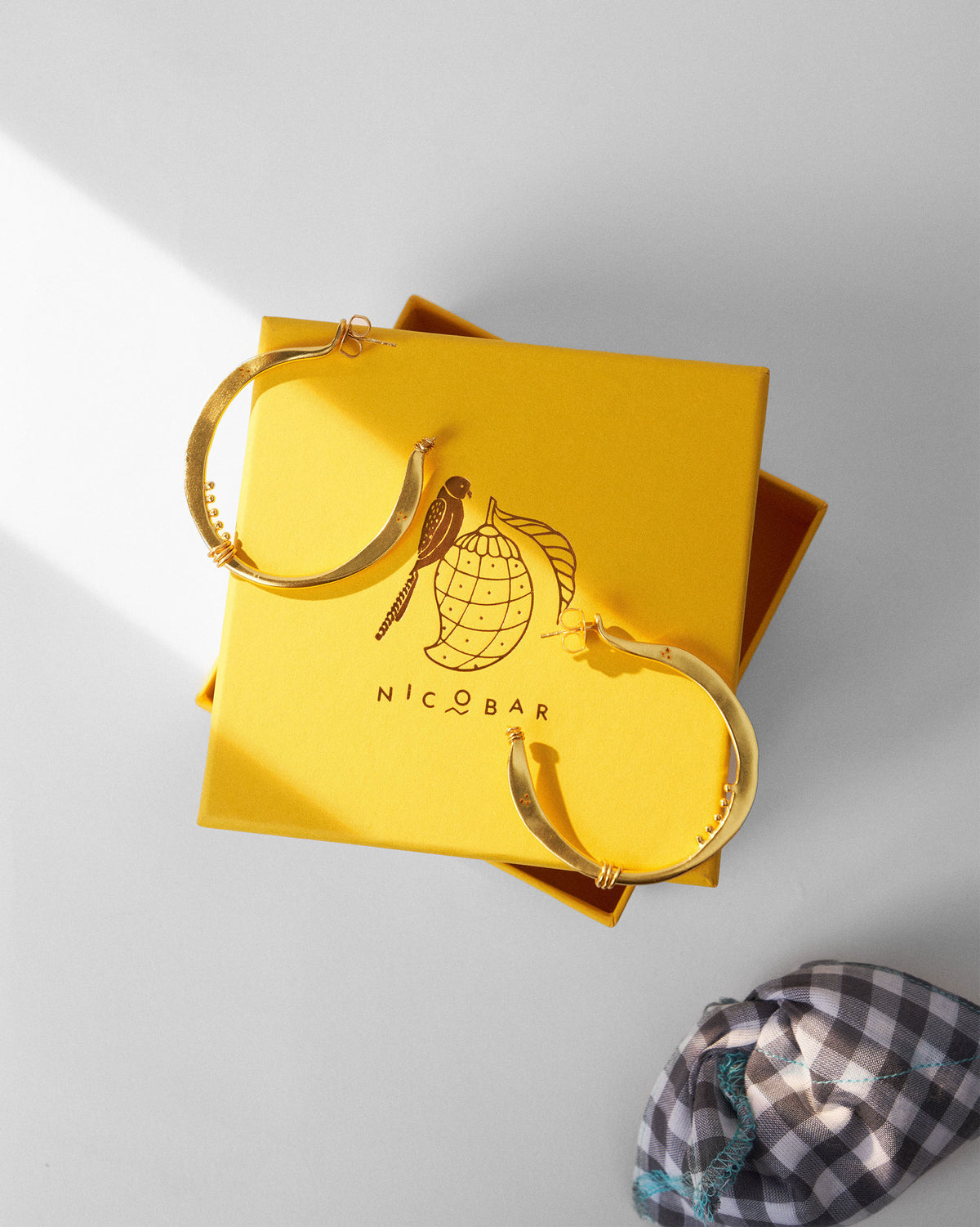 Large gold Qala balis on a yellow Nicobar gift box.