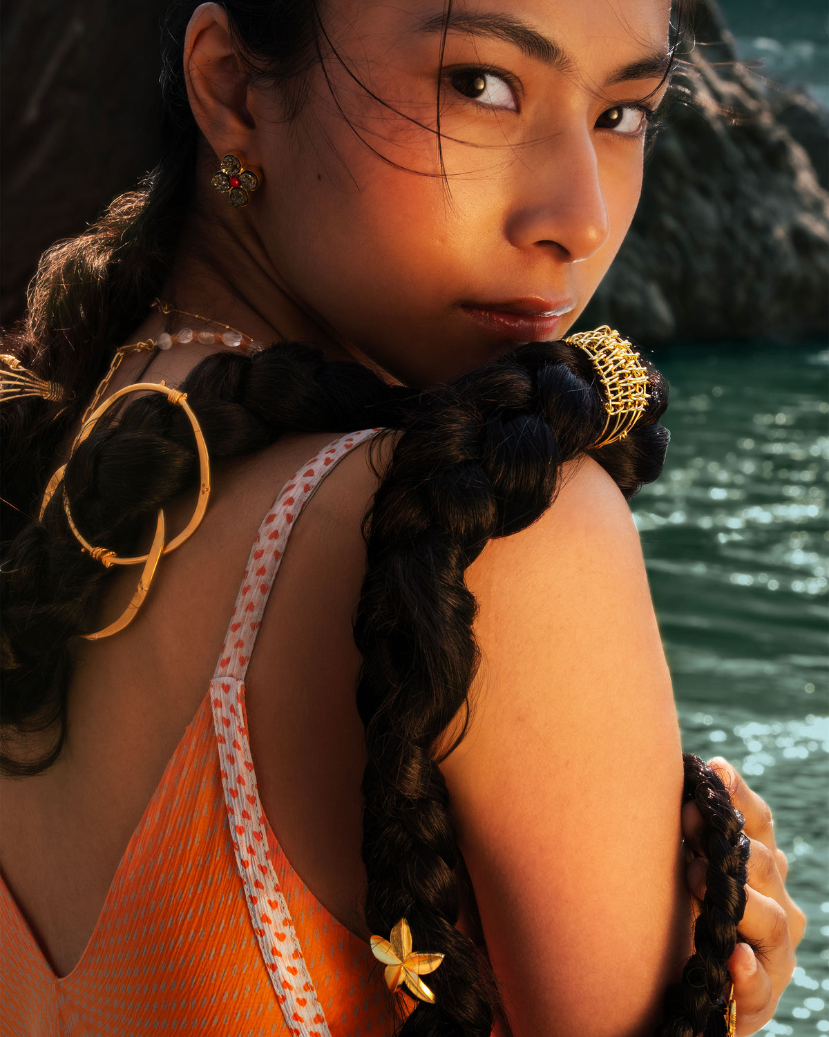 Person wearing gold jewellery styled in a braid.