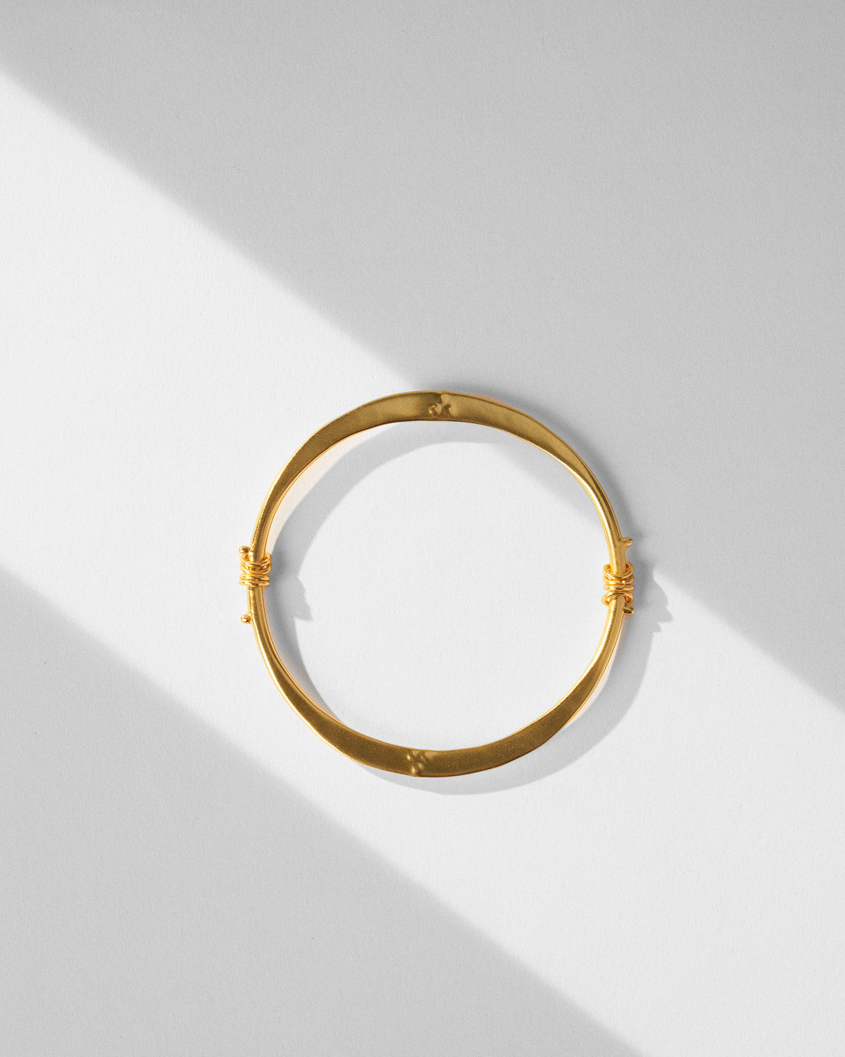 Gold qala bangle laid flat showing coiled side details.