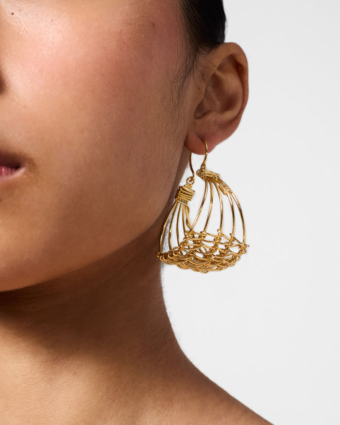 Side profile of a gold Shore wire cage bali on a person.