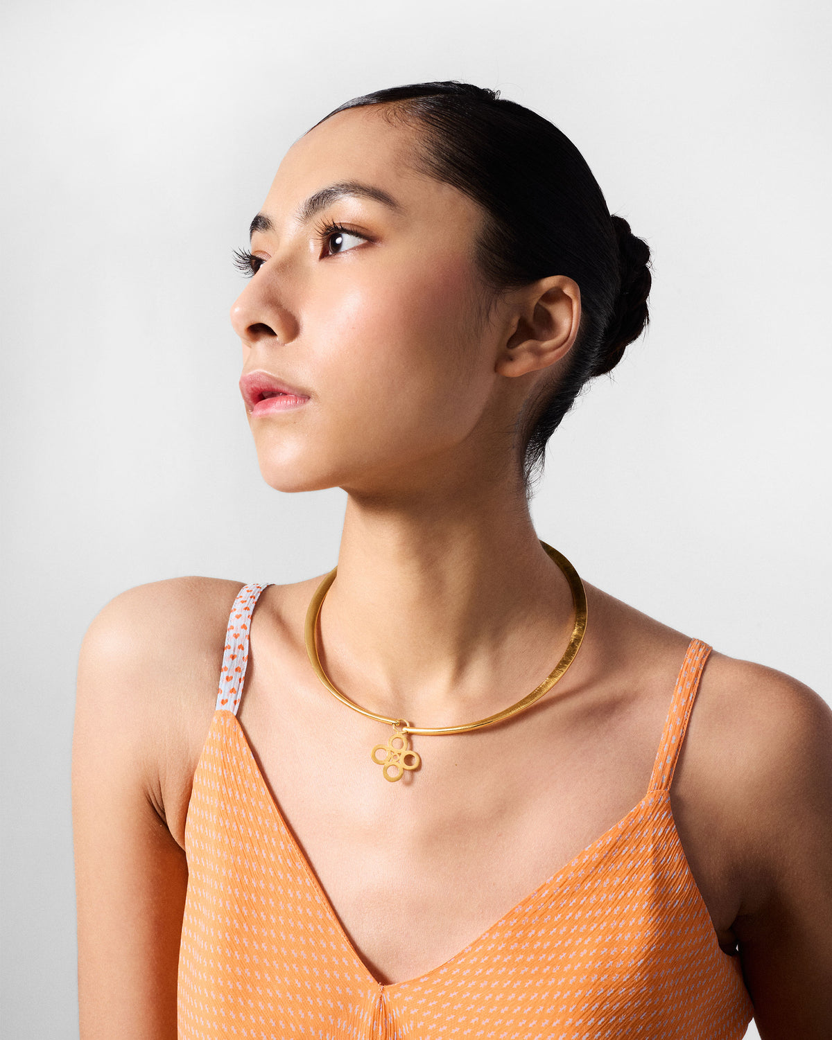 Person wearing a gold sindhu choker with a floral pendant.