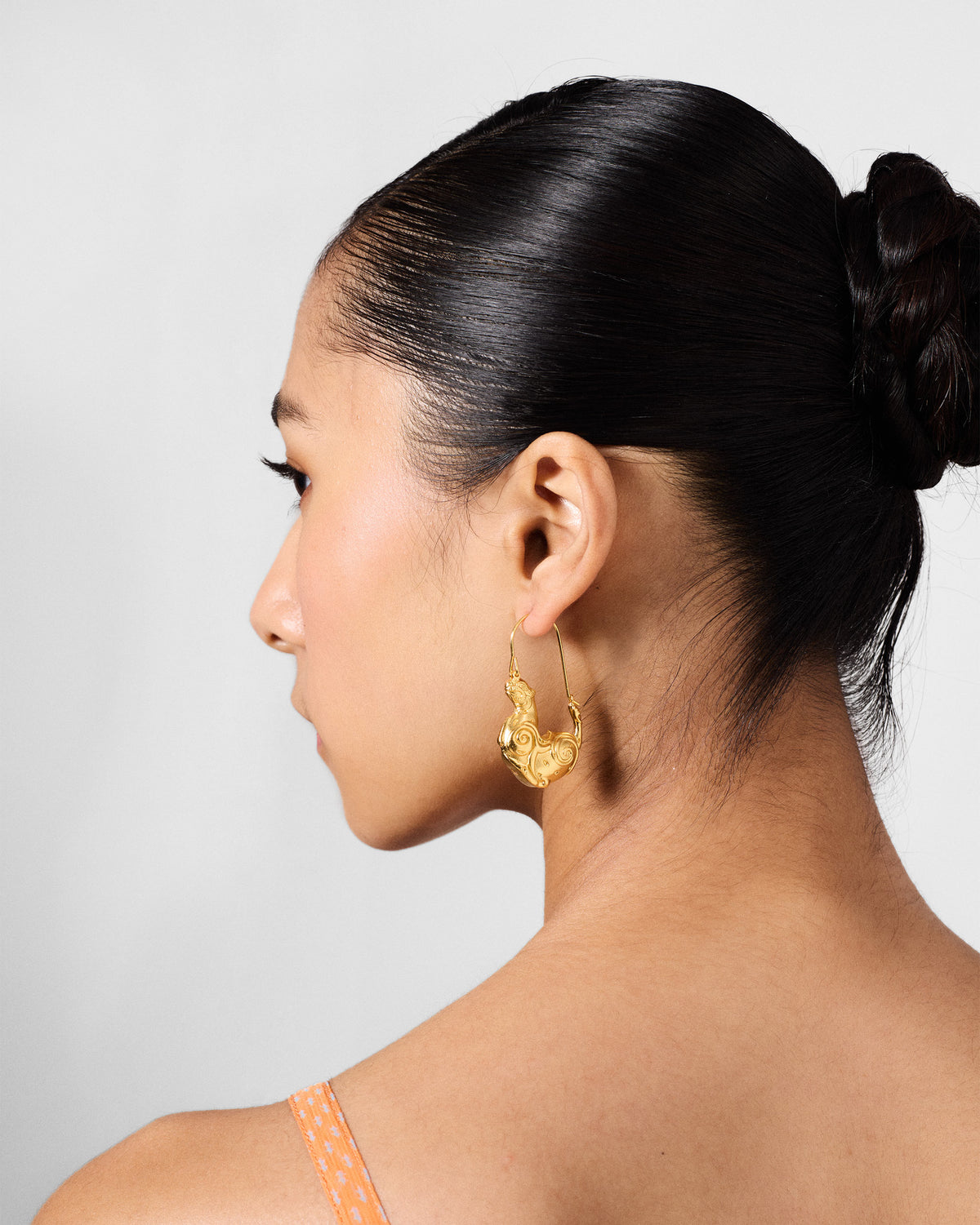 Side profile of a gold sculpted leopard hoop earring.