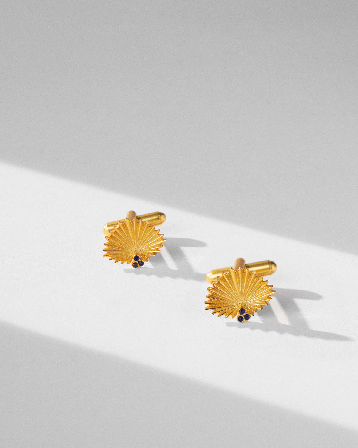 Pair of gold Palm Leaf Cufflinks with fan-shaped fronts and dark stones.