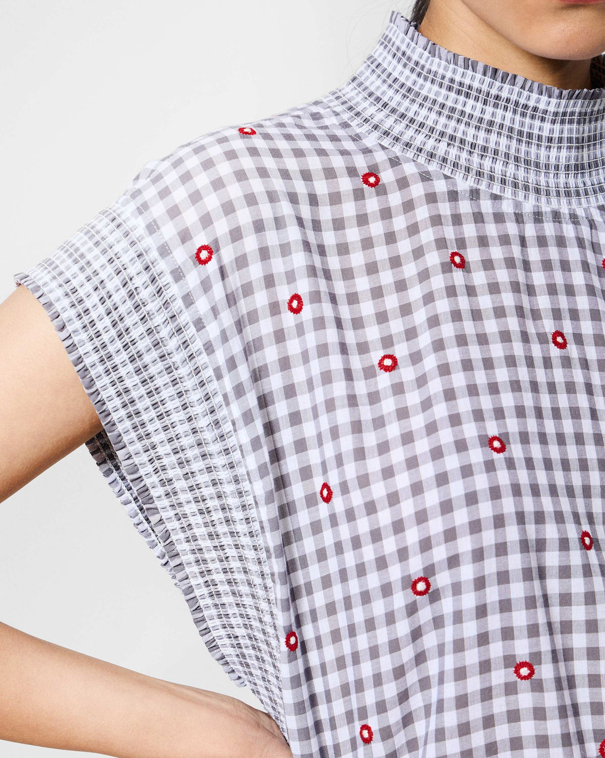Close-up of grey and white Lehar top fabric with red embroidery and smocked collar.
