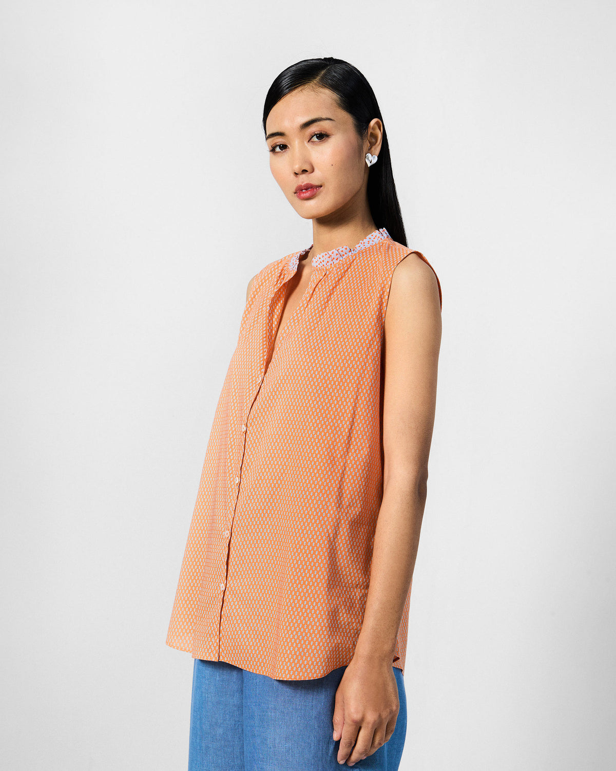 Three-quarter view of an orange printed Roh top on a person.