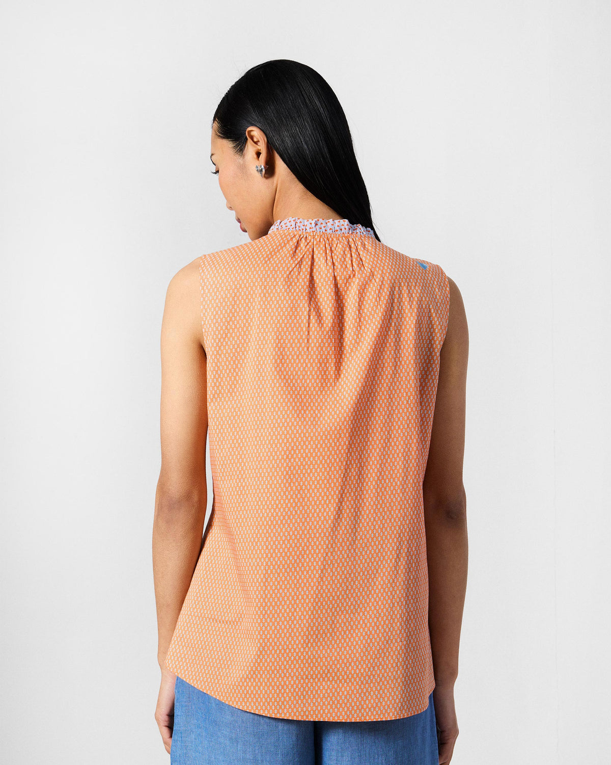 Back of an orange printed Roh top with a ruffle collar.