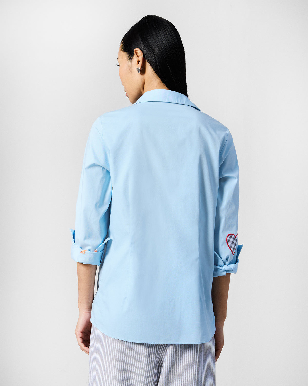 Back of an ice blue Ela shirt showing a gingham heart patch on the sleeve.