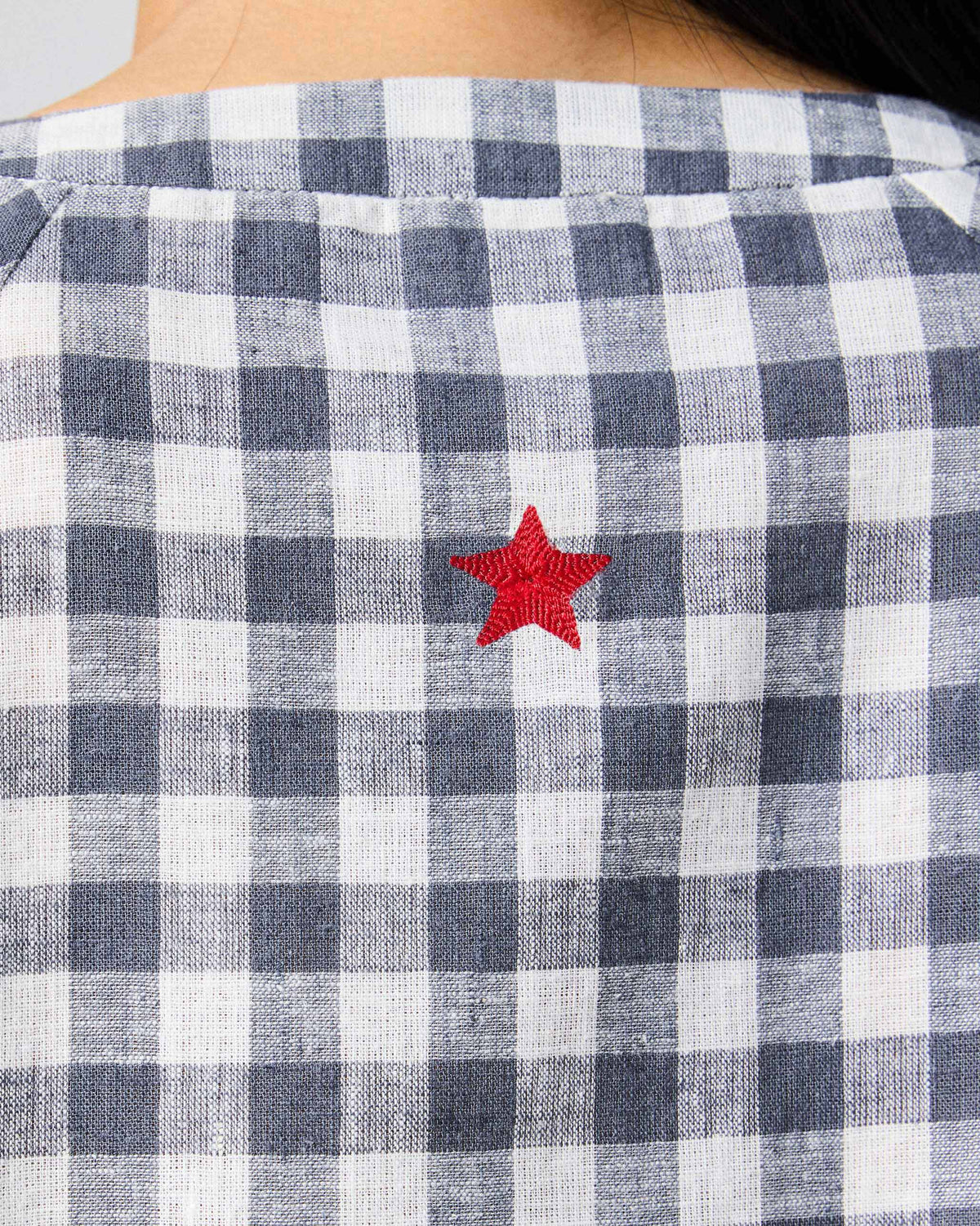Close-up of the red star embroidery on a charcoal and white checked Zil top.