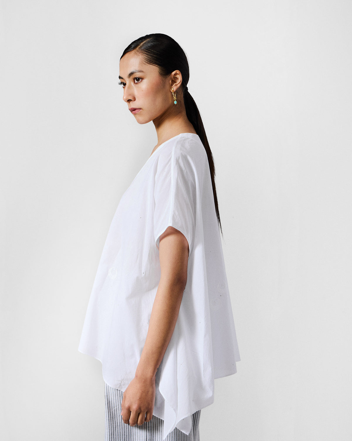 Side view of a white oversized top with wide short sleeves.