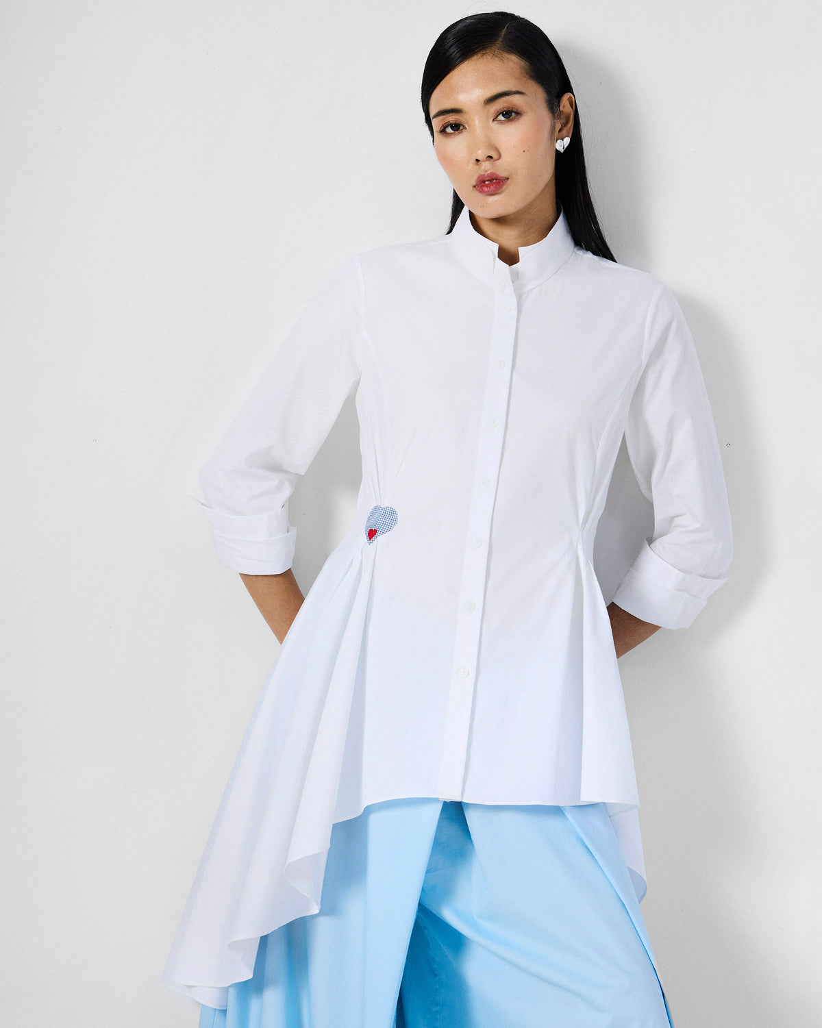 Person wearing a white Rai top with an asymmetric hem and blue heart.