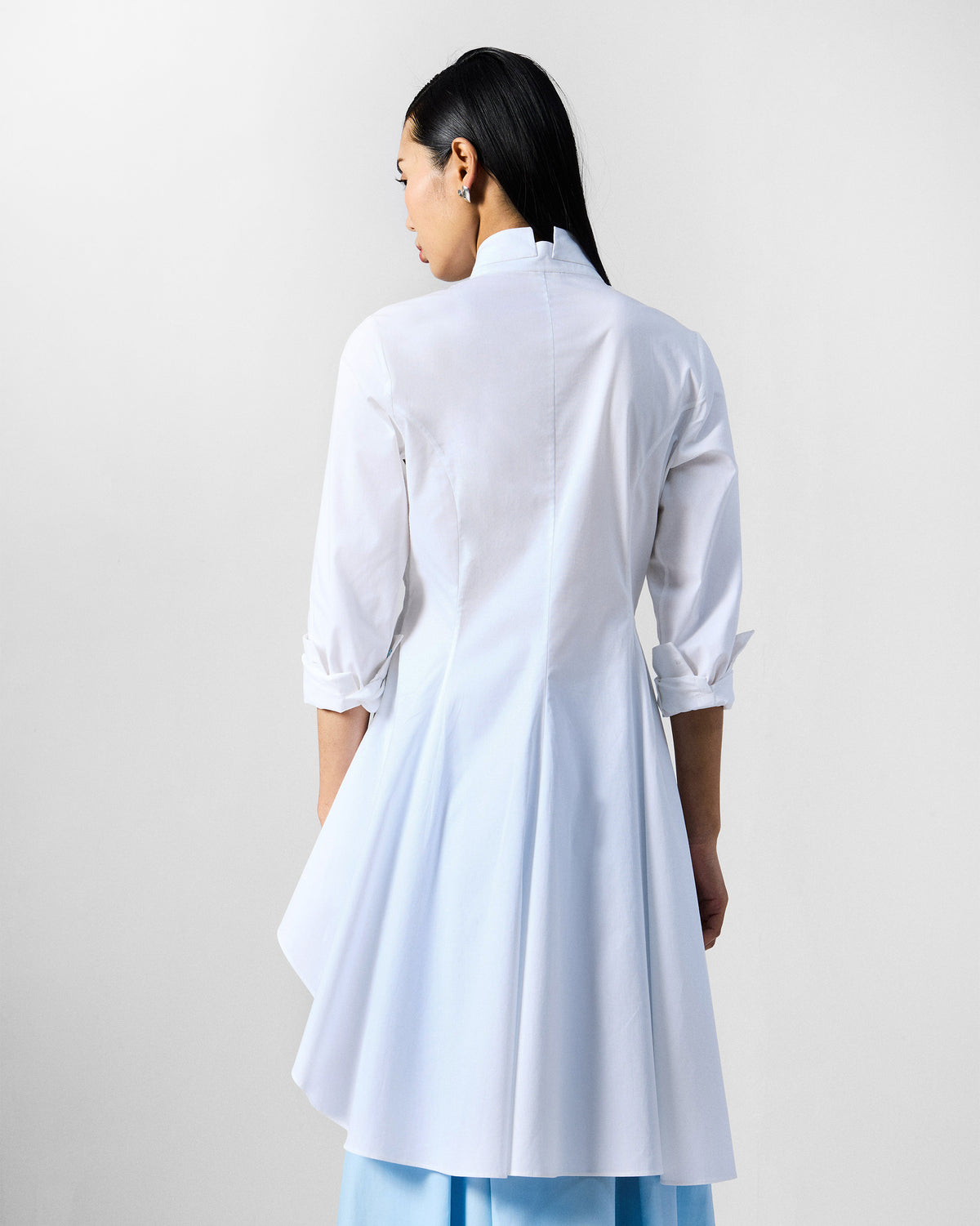 Back of a white Rai top with an asymmetric flared hem.