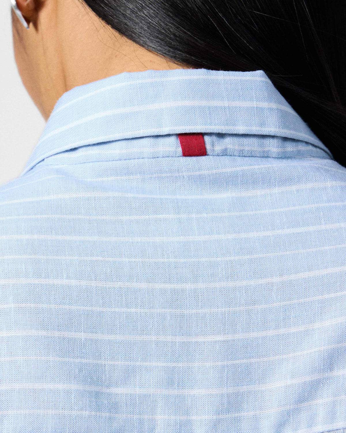 Close-up of the red neck tab on a blue and white striped Vaah top.