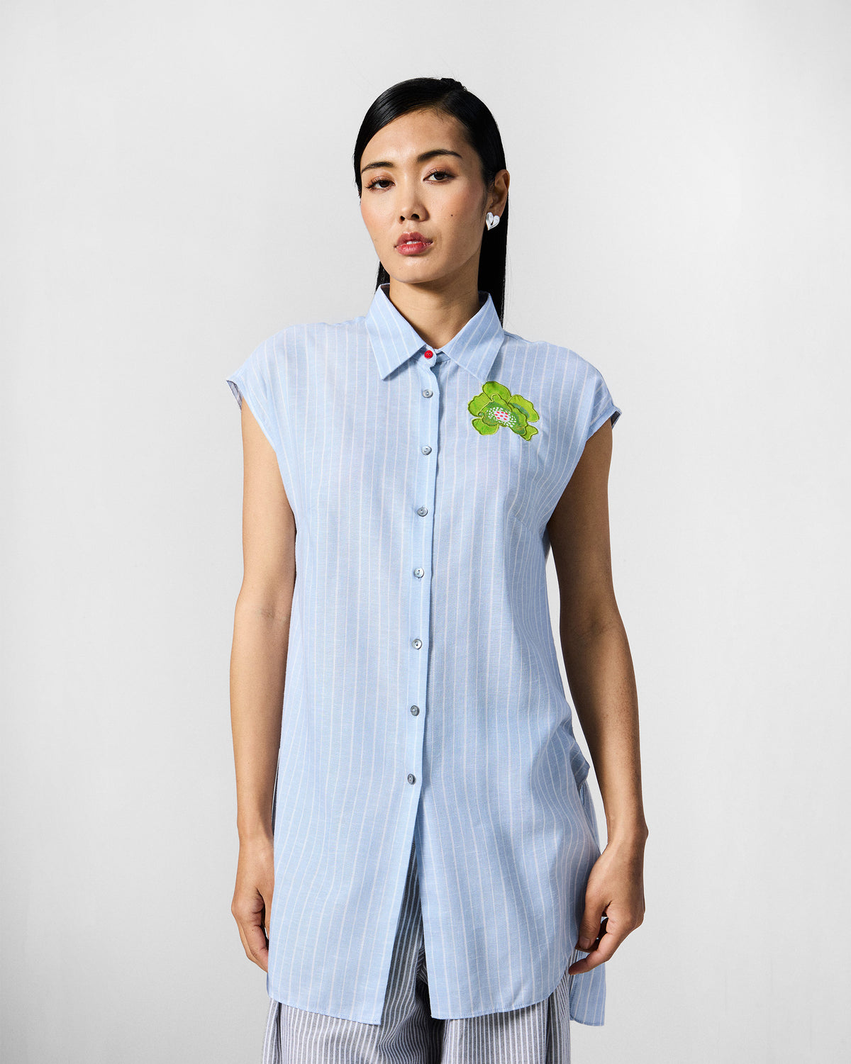 Person wearing a blue and white striped Vaah top with a lime green flower applique.