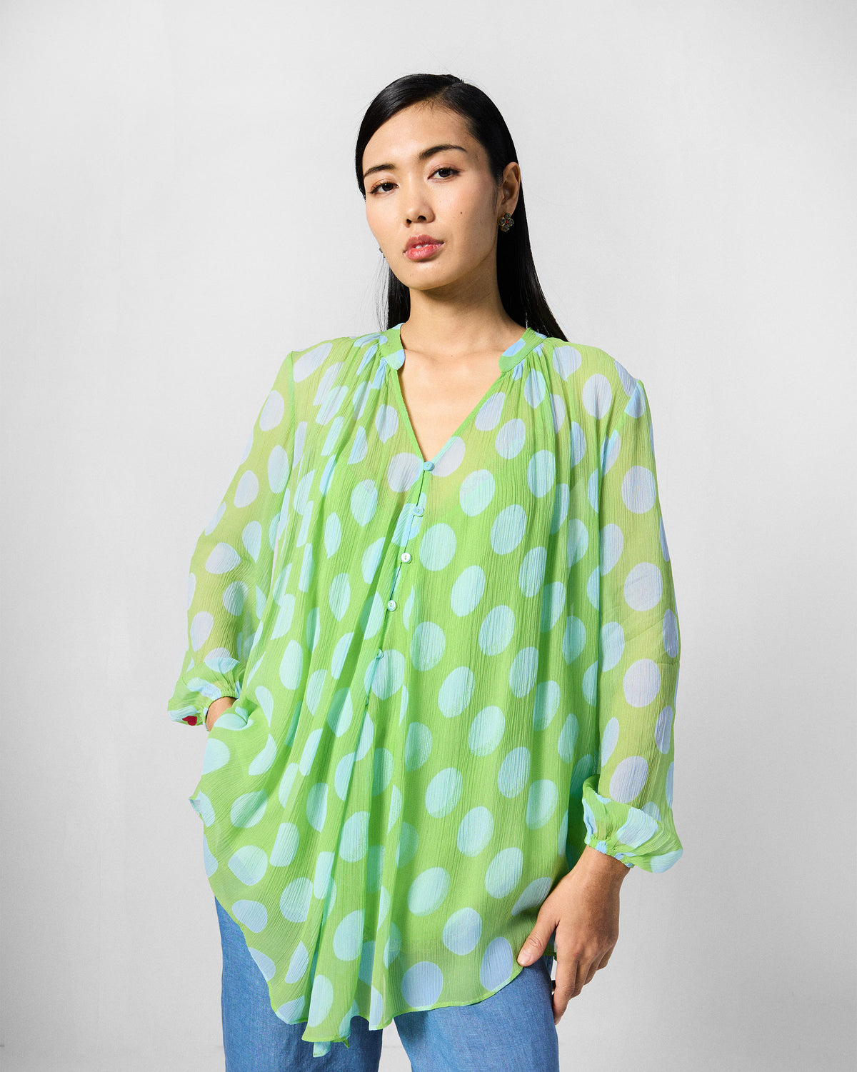 Person wearing a green Jora top with ice-blue polka dots and a band collar.